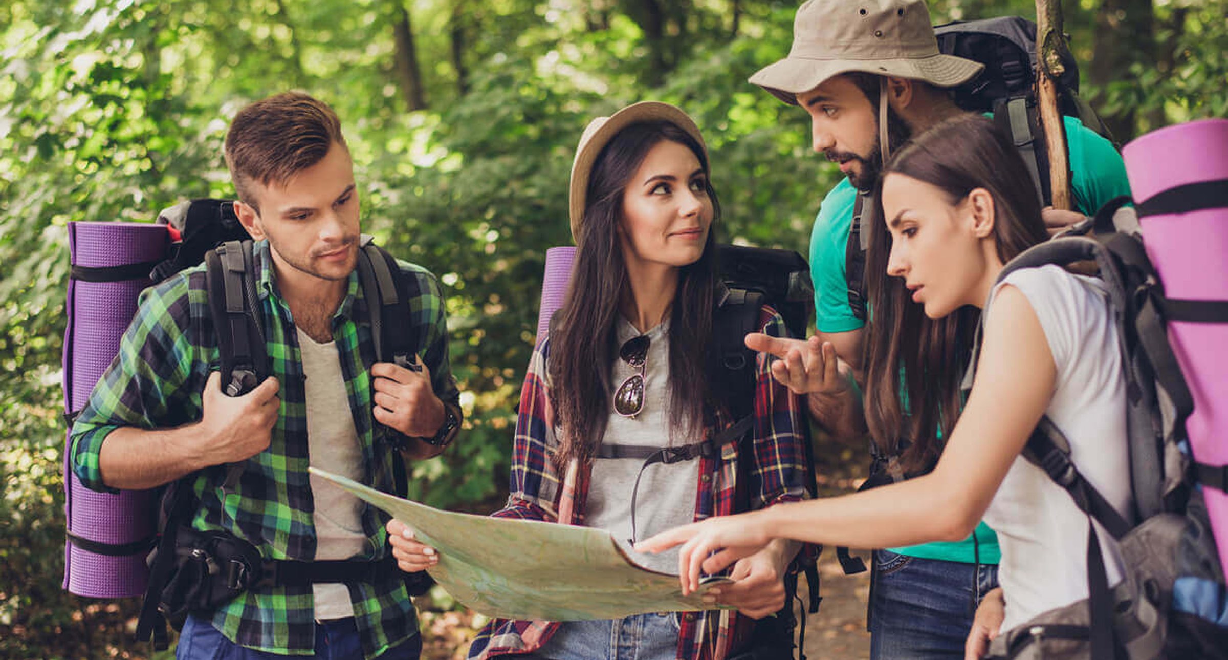 Four young adults looking at a map in a forest